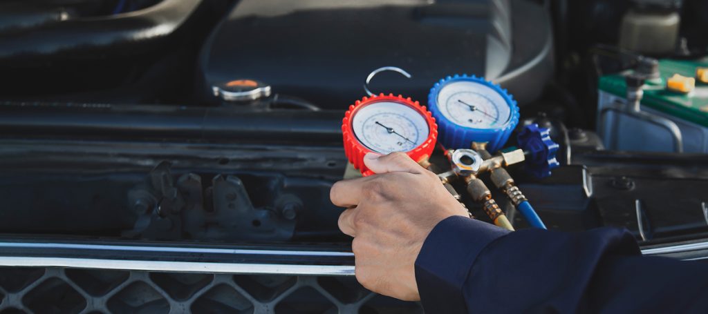 technician servicing a vehicle air conditioning system